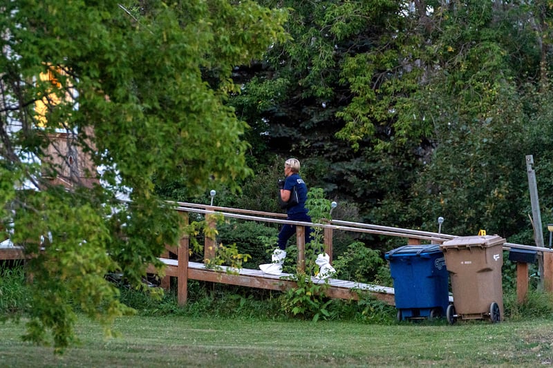 A coroner enters a house at the scene of a stabbing in Weldon, Saskatchewan. AP