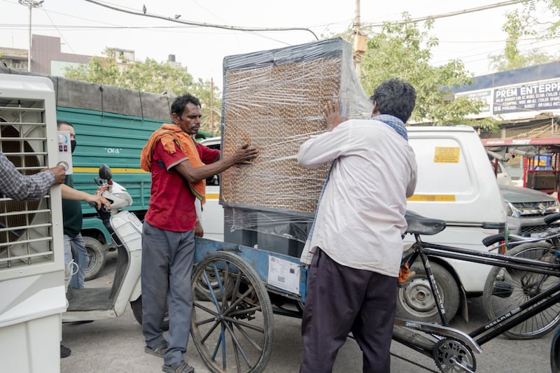 Men carry an air cooler onto a bicycle in New Delhi. The weakening rupee is affecting the country's imports, making goods more expensive for consumers. Bloomberg