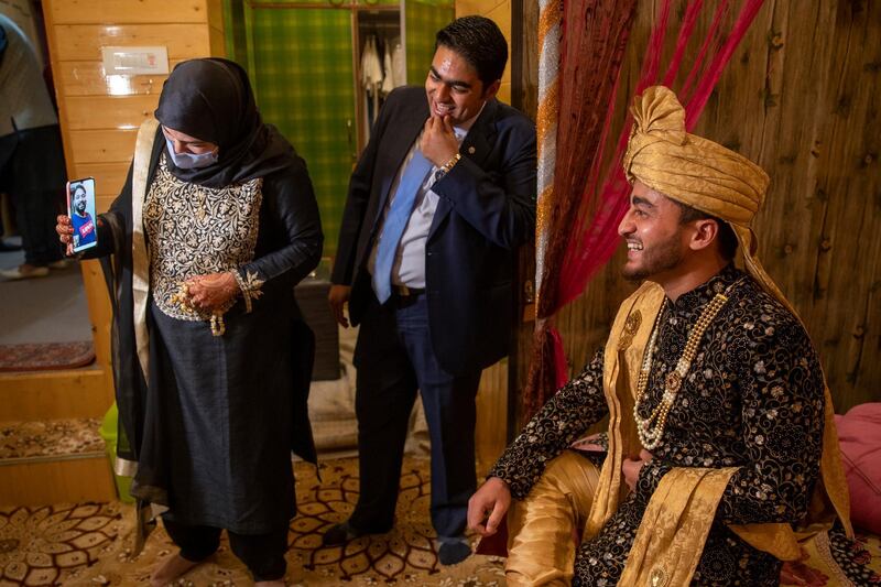 Khusheeba Munir holds the cell phone as her husband Azhar Mahmood, who tested positive for Covid-19 and was not able to attend the marriage, shares a lighter moment with his cousin and groom Haseeb Mushtaq, during a wedding ceremony on the outskirts of Srinagar, Indian controlled Kashmir. AP Photo