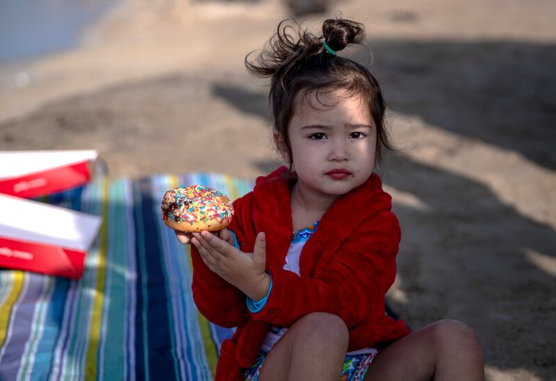 A young bystander enjoys a breakfast doughnut.