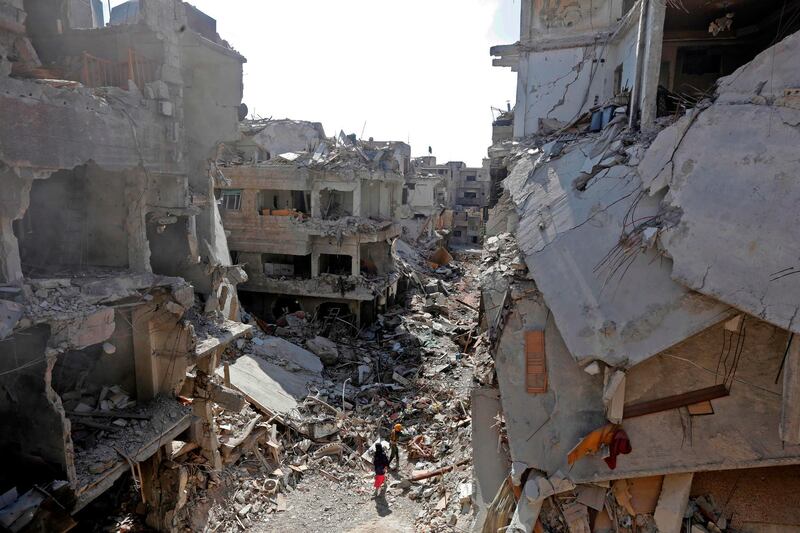 Women walk in the rubble of the Yarmuk Palestinian refugee camp in Damascus. AFP