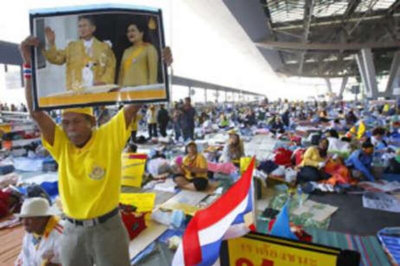 A People's Alliance for Democracy protester holds a portrait of Thai king and queen during a rally at the besieged Suvarnabhumi international airport in Bangkok on Dec 1 2008.