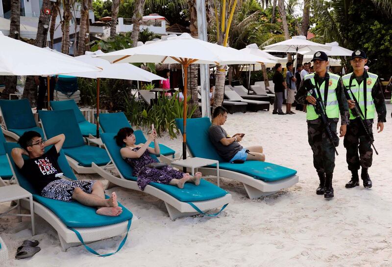 Policemen walk past tourists, one day before the temporary closure of the holiday island Boracay, in the Philippines on April 25, 2018. Erik De Castro / Reuters