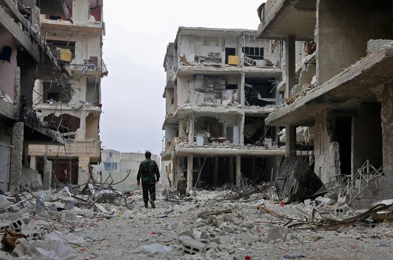 TOPSHOT - Syrian government soldiers walk down a street past destroyed buildings in the town of Hazzeh in Eastern Ghouta, on the outskirts of the Syrian capital Damascus, on March 28, 2018. / AFP PHOTO / STRINGER