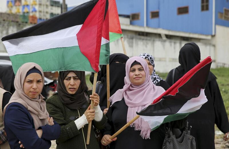 Women wave their national flags during a rally marking the 41st anniversary of Land Day, on the Palestinian side of the Beit Hanoun border crossing between Israel and the Gaza Strip. Adel Hana / AP Photo