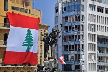 A Lebanese flag is seen on Le Gray hotel next to the Martyrs' Monument in downtown Beirut four days after a monster explosion killed more than 150 people and disfigured the Lebanese capital. AFP