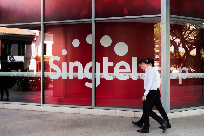 A pedestrian walks past a Singapore Telecommunications Ltd. (SingTel) store in Singapore, on Monday, Feb. 29, 2016. Singapore's Infocomm Development Authority plans to auction additional mobile spectrum this year as it seeks to lure a new entrant to compete with the city's three existing providers. Photographer: Nicky Loh/Bloomberg