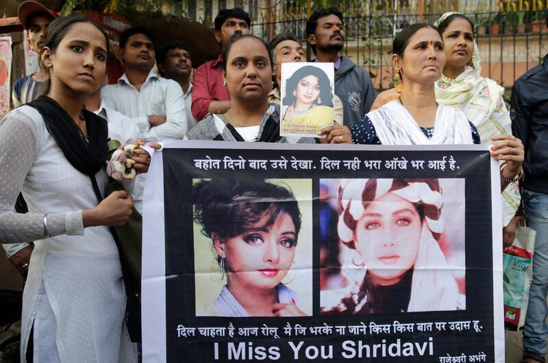 Mourners hold Sridevi posters as they wait outside her residence to pay their last respects. Rafiq Maqbool / AP Photo