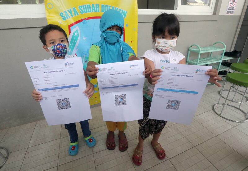Pupils show their vaccination certificates during an inoculation drive in Jakarta, Indonesia. EPA