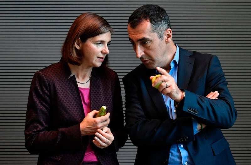 The top candidates of the German Greens Party "BÜNDNIS 90/DIE GRÜNEN" Cem Özdemir and Katrin Göring-Eckardt eat a pear and an apple as they confer before their party's first parliamentary group meetings after the general elections on September 26, 2017, in Berlin.  / AFP PHOTO / John MACDOUGALL