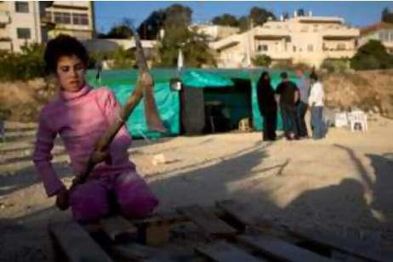 A girl from the al-Kurd Palestinian family chops wood outside a newly erected tent for the family near their house in Jerusalem on November 11, 2008. The east Jerusalem family from the Sheikh Jarrah neighbourhood was evicted from their house on November 9 in the wake of a prolonged court battle with Jewish settlers and are now refugees yet again, after living at the neighbourhood since 1956. AFP PHOTO/YOAV LEMMER *** Local Caption ***  683782-01-08.jpg