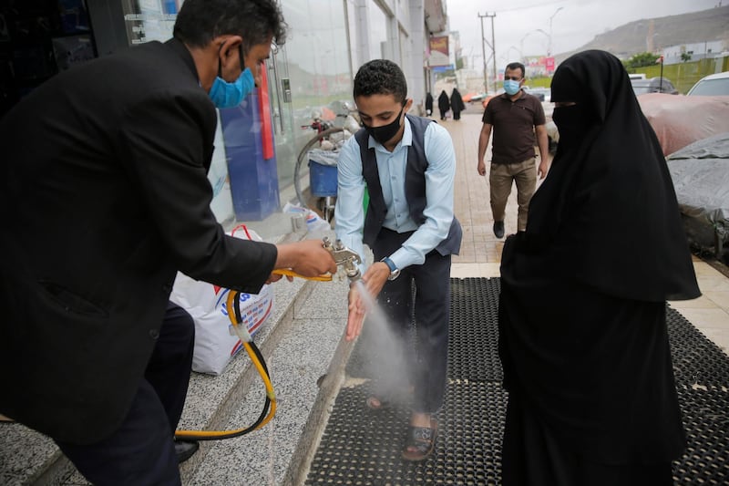 A worker disinfects a shopper's hands as a preventive measure against the spread of the new coronavirus before they enter a mall in Sanaa. AP