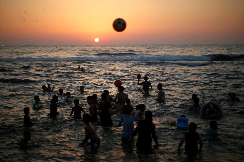 Palestinians play with balls as they swim in the Mediterranean Sea on a hot day, in the northern Gaza Strip. Reuters