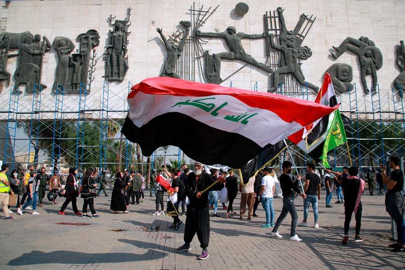 A protester waves a large Iraqi flag in Tahrir Square during a demonstration calling for the government to resign, in Baghdad, Iraq, Sunday, Nov. 15, 2020. (AP Photo/Khalid Mohammed)