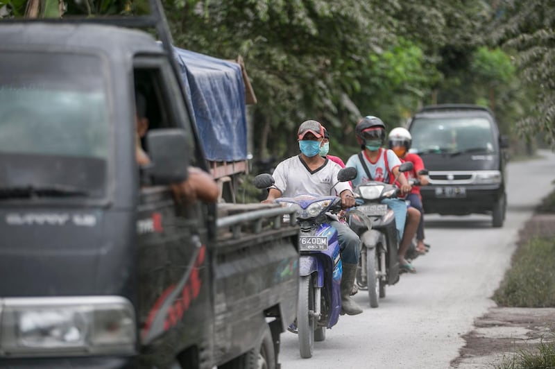 Motorists drive on a road covered by volcanic ash as Mount Agung volcano spews ash in Karangasem, Bali, Indonesia. Made Nagi / EPA