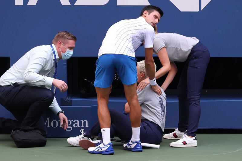 Novak Djokovic tends to a line judge he hit with the ball during his fourth-round match against Pablo Carreno Busta at the 2020 US Open. The Serb was subsequently disqualified. AFP