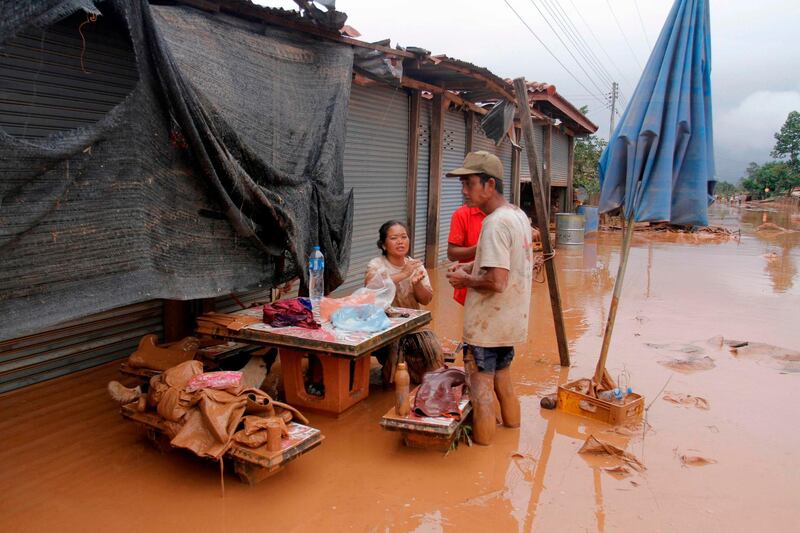 Residents rest in front of a flooded establishment at a village in Sanamxai, Attapeu province. AFP