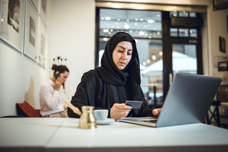 Muslim young woman shopping online at cafe using credit card