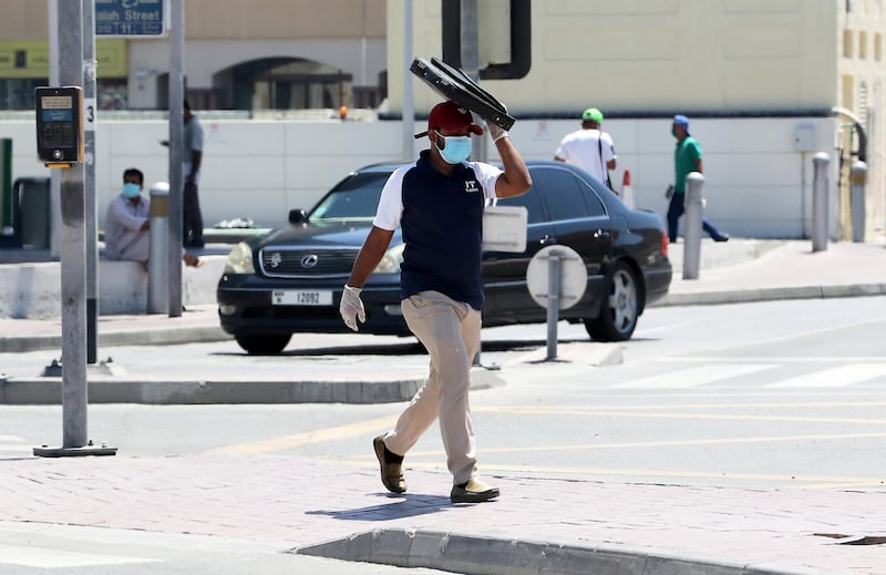 DUBAI, UNITED ARAB EMIRATES , May 6 – 2020 :- A person wearing protective face mask and covering his face with laptop bag on a hot day in Bur Dubai area in Dubai. UAE government ease the coronavirus restriction for the residents around the country. (Pawan Singh / The National) For News/Standalone/Online/Stock/Instagram