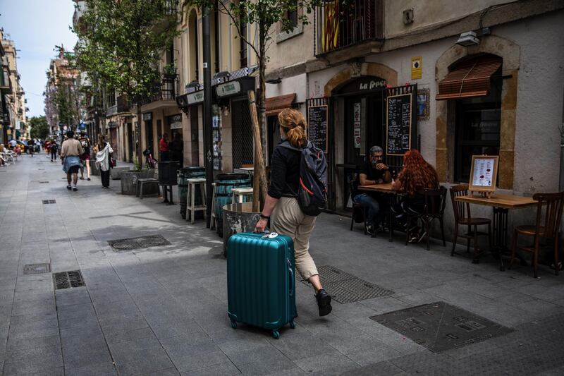 A tourist wheels luggage in the Barceloneta district in Barcelona, Spain. Bloomberg