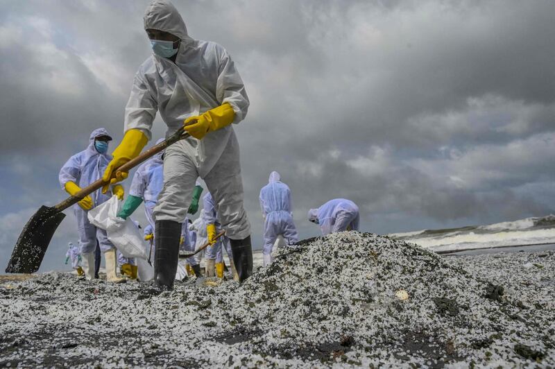 Sri Lankan Navy soldiers remove debris washed ashore from the Singapore-registered container ship 'MV X-Press Pearl', which is still burning, a ninth consecutive day, off Colombo harbour in Sri Lanka. AFP