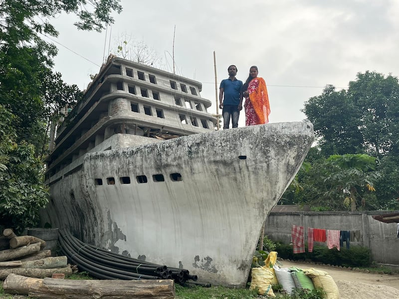 Mintu and Iti Roy stand proudly on the bow of their boat-shaped home. Photo: Anurag Khat