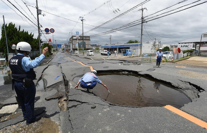 Police check a collapsed road following an earthquake in Takatsuki, north of Osaka prefecture. AFP