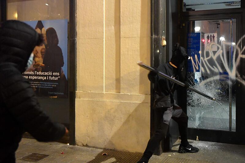 A protester breaks the glass of a bank branch's door during clashes with Catalan regional police forces. AFP