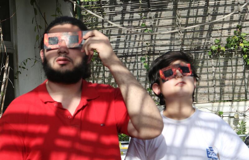 A father and son use special protective glasses to observe a partial solar eclipse from Damascus, Syria. EPA
