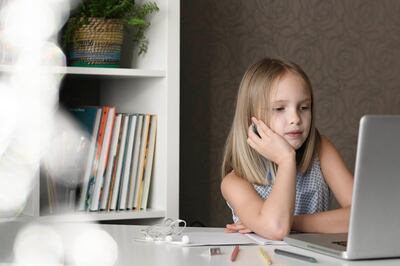 Girl sitting at table at home using laptop. Getty Images