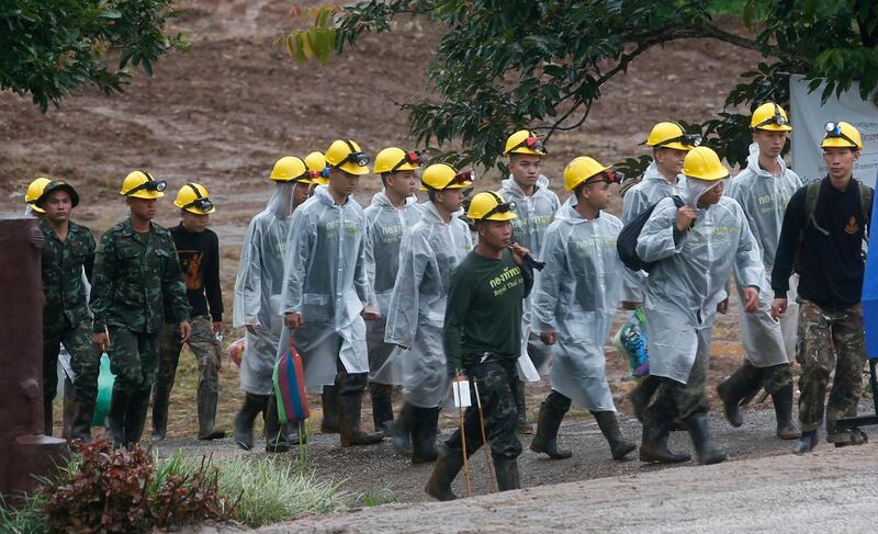 Rescuers walk toward the entrance to a cave complex. AP Photo