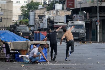 Palestinians throw rocks at Israeli security forces during a military raid in the West Bank city of Nablus. AP
