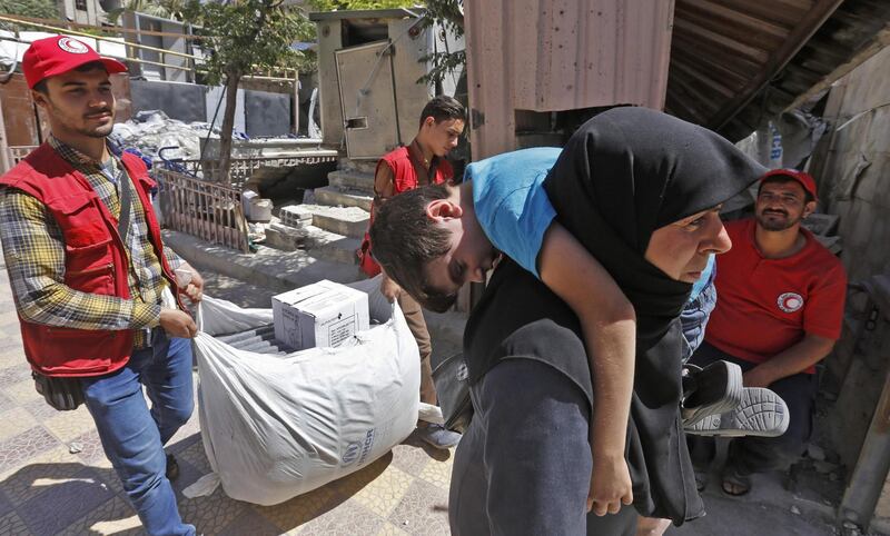 Members of the Syrian Arab Red Crescent distribute humanitarian aid to residents of the town of Douma as part of a humanitarian assistance provided by France in the region of Eastern Ghouta on July 26, 2018. Residents of Eastern Ghouta had faced five years of crippling siege during which even the most basic food and medicines were virtually unaffordable, forcing around 400,000 people to rely on UN aid deliveries.
The assistance was part of a humanitarian aid operation coordinated between Moscow and Paris, the first such mission between Russia and a Western country. / AFP / LOUAI BESHARA
