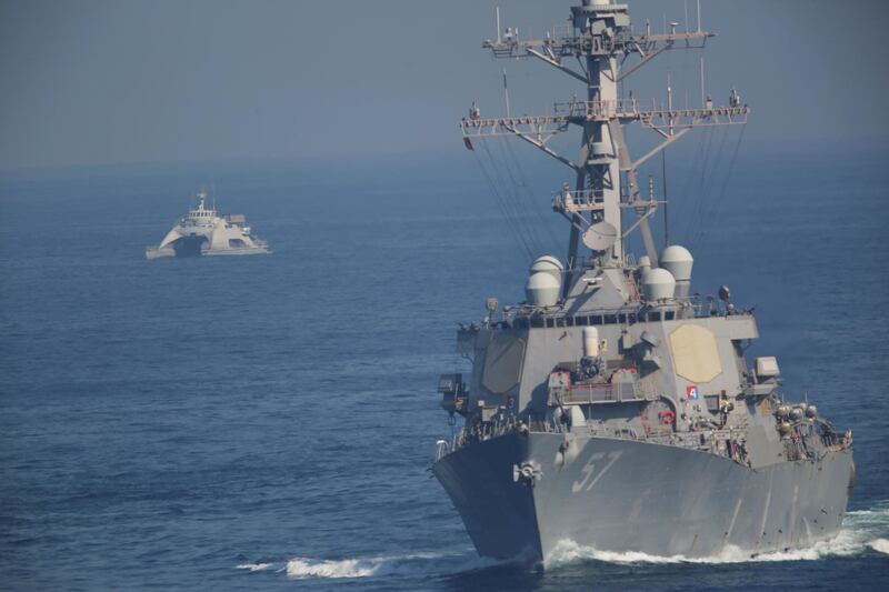 The USS Mitscher, part of a strike group led by the USS John C. Stennis aircraft carrier, sails as an Iranian Revolutionary Guard vessel shadows it on Friday, Dec. 21, 2018. The U.S. aircraft carrier sailed into the Persian Gulf on Friday, becoming the first since America's withdrawal from the Iran nuclear deal and breaking the longest carrier absence in the volatile region since at least the Sept. 11 terror attacks. (AP Photo/Jon Gambrell)