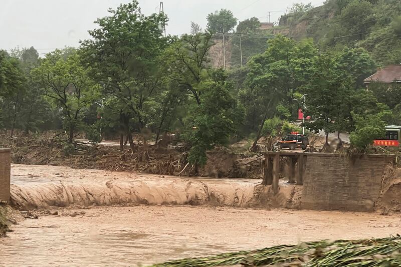 The remainder of a bridge that was washed away by floods along a river in Qingyang, in north-west China's Gansu province, on Saturday. AP