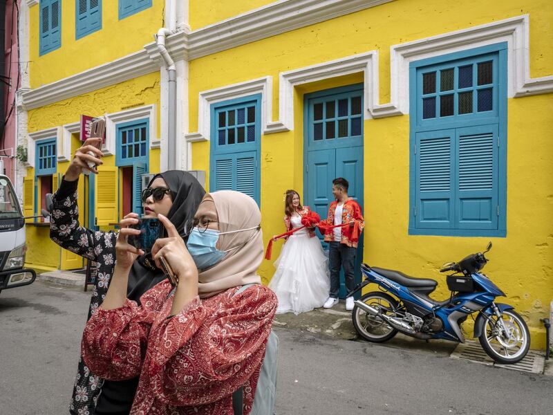 Visitors pose for photographs at a street in Kuala Lumpur, Malaysia. Bloomberg