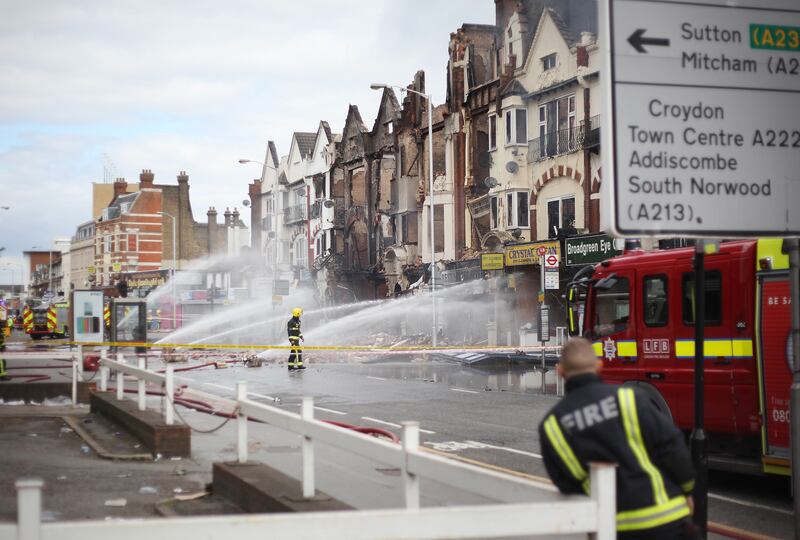 Fire fighters damp down smouldering buildings on London Road, Croydon.