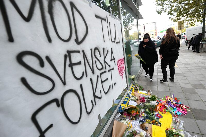 A woman lays flowers in front of a sign which reads 'courage to the Swedish people' near the scene of the fatal shooting in Brussels. AP