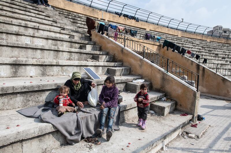 Displaced Syrians sit on the tribunes of a stadium which has been turned into a makeshift refugee shelter in Idlib, Syria. Getty