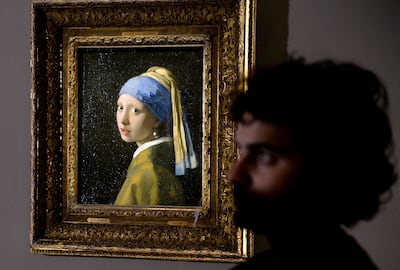 A man stands next to the masterpiece "Girl with a Pearl Earring" by Dutch painter Johannes Vermeer during a preview of the exhibition "The Myth of the Golden Age, From Rembrandt to Vermeer". AFP