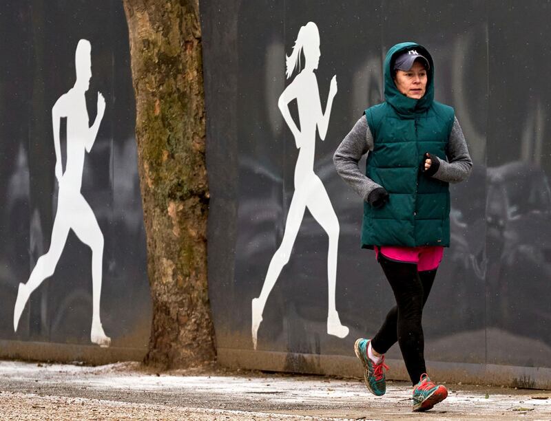 A runner wrapped up against the freezing cold temperatures, runs outside Richmond Park in London, Monday Feb. 8, 2021.  The nation is locked down because of the coronavirus, but people are allowed out to exercise although snow and ice has swept across the region and is predicted to stay over the coming days. (John Walton/PA via AP)