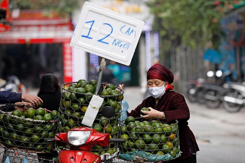 An elderly woman buys oranges on a street in Hanoi, Vietnam. EPA