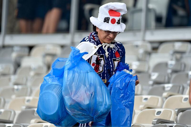 A Japanese fan picks up litter left on the stands at the Mineirao Stadium in Belo Horizonte, Brazil. AFP