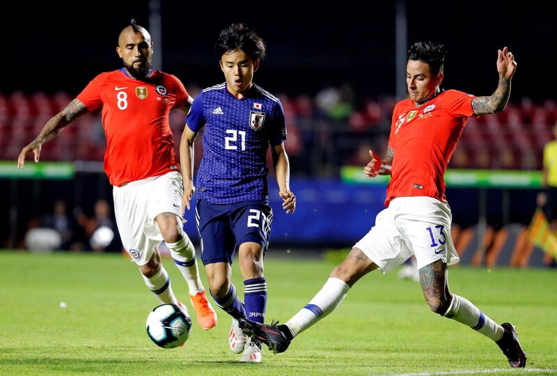 Takefusa Kubo, centre, of Japan vies for the ball with Arturo Vidal and Erick Pulgar of Chile. EPA