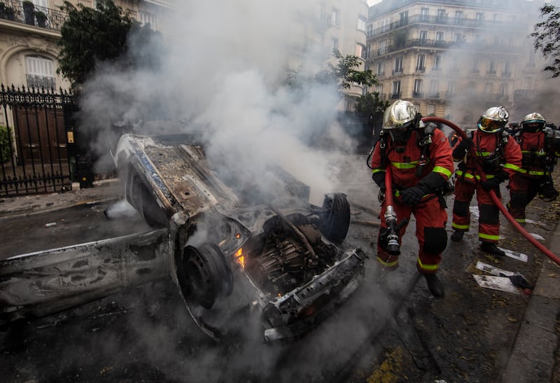 Firefighters work to put out cars set alight on a road near the Arc de Triomphe in December 2018 after yellow vest demonstrations.