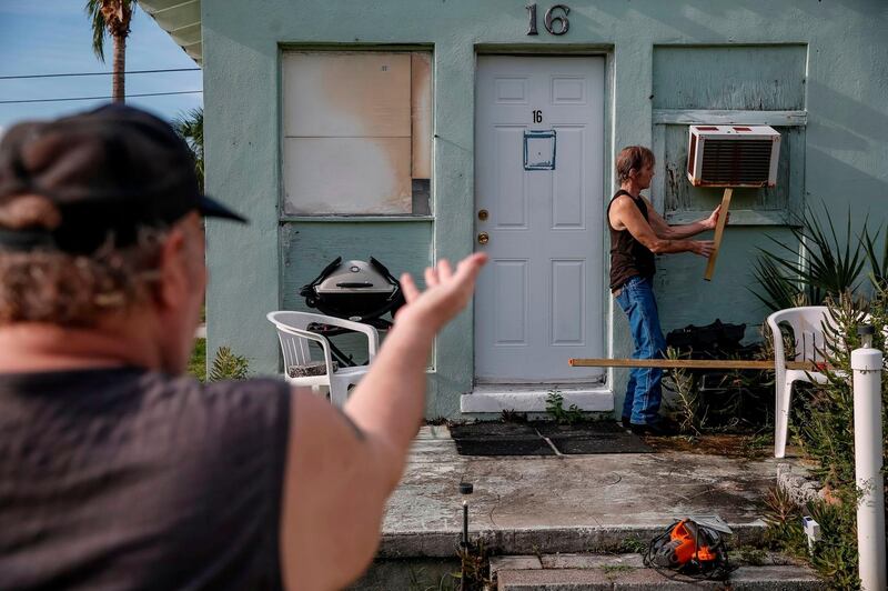 Riverside Mobile Home Park residents Joe Lewis and Rob Chambers work to secure Joe's air conditioner. AFP