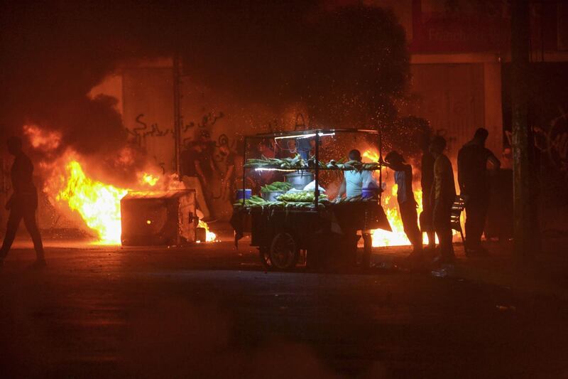 Lebanese anti-government protesters buy corn from a street vendor next to burning garbage bins during clashes with security forces in the northern port city of Tripoli amid fresh protests over a spiralling economic crisis.  AFP