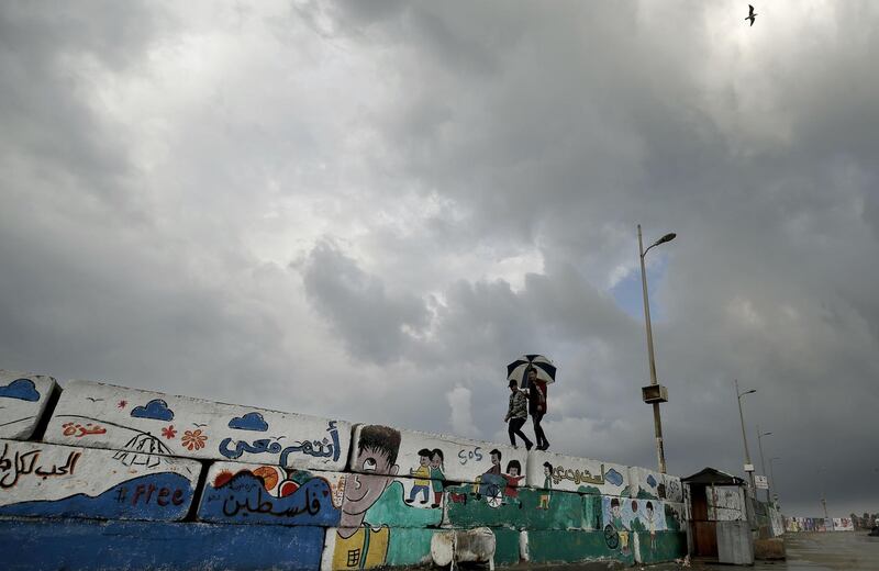 Palestinian youths walk over a wall decorated with graffiti following a rainstorm in Gaza City.  AFP