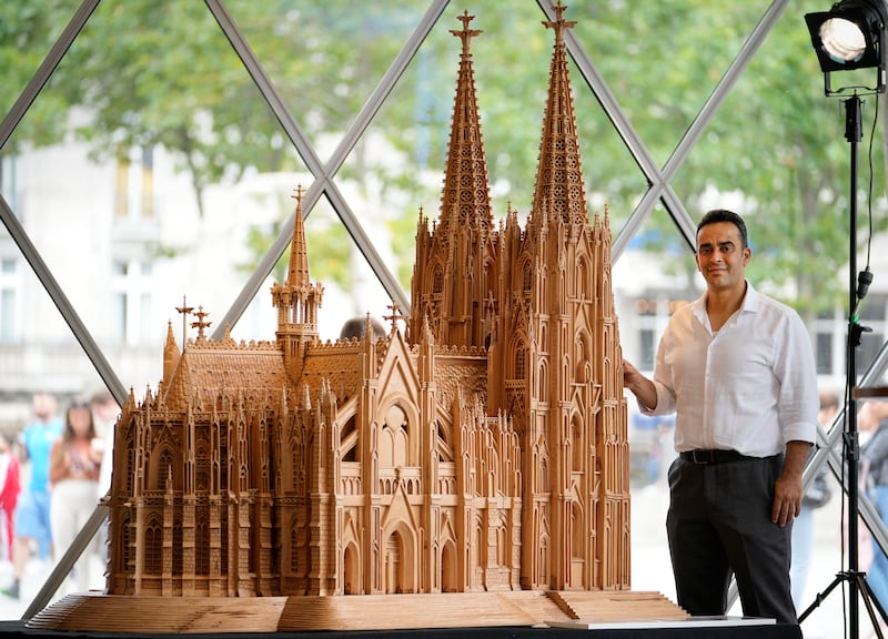 Woodcarver and artist Fadel Alkhudr from Syria poses beside his wooden model of Cologne Cathedral in the German city. He fled the civil war in his home country in 2015. AP