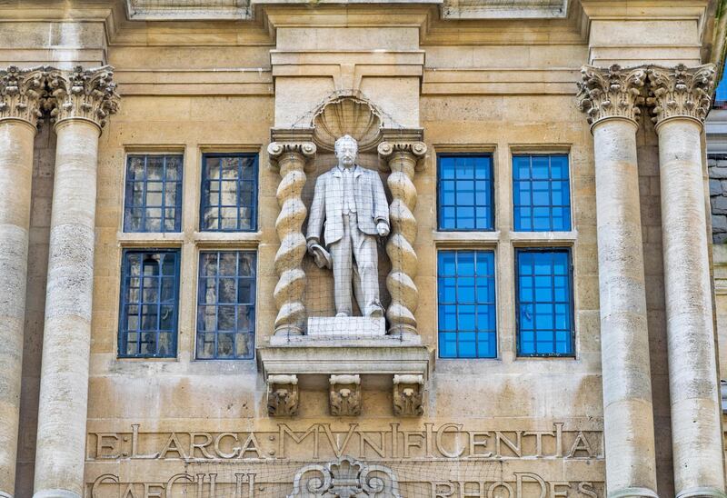 G2GCF8 OXFORD CITY CECIL RHODES THE STATUE LOOKS DOWN FROM THE FRONT OF ORIEL COLLEGE OXFORD SEEN FROM THE HIGH STREET